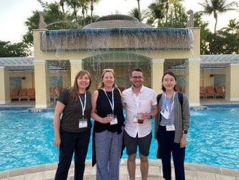 Phot of lab members posing at conference in front of a pool
